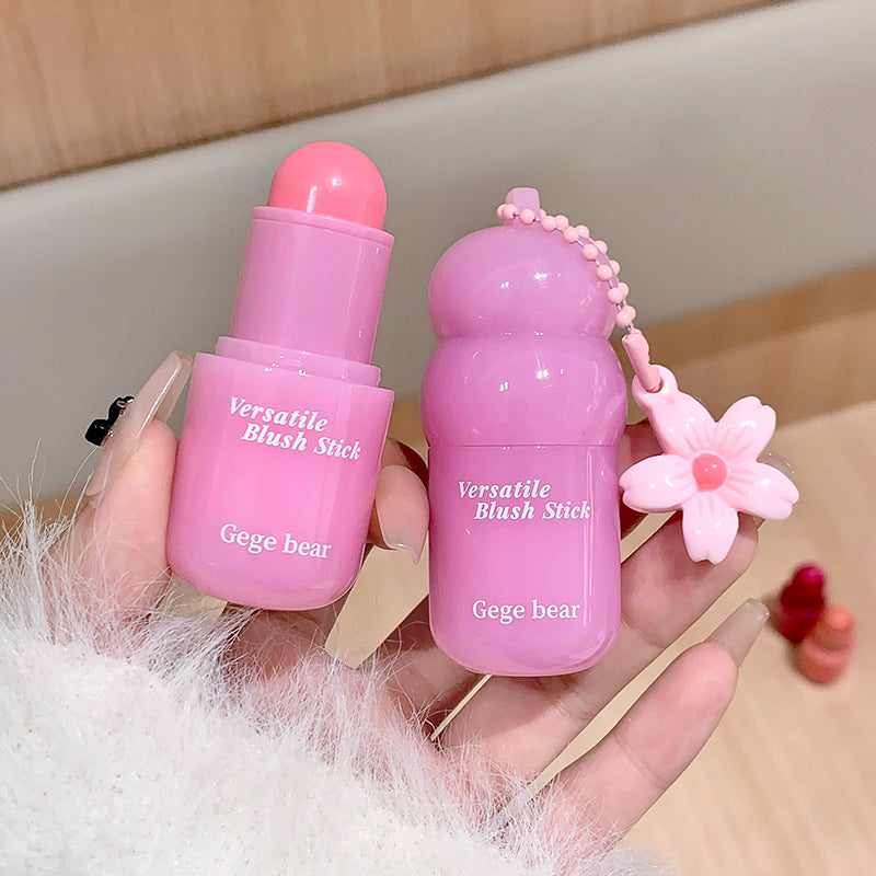 Two pink 'Versatile Blush Stick' by Gege bear held in a hand with a light background.