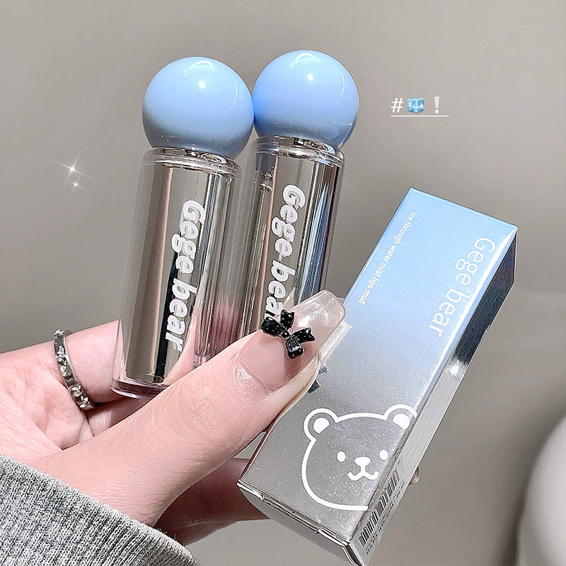 Two clear lip balms with blue caps held by a hand, next to their packaging box.