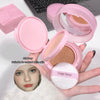 Pink compact powder with a mirror and puff, held by a hand, on a white background.