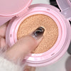 Pink compact powder with a sponge puff inside, held by a hand.