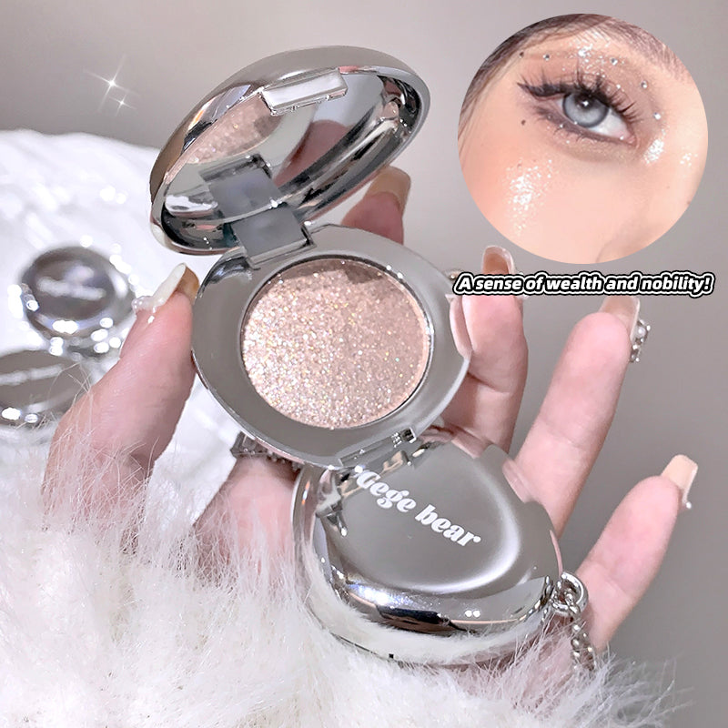 Compact mirror with glittery eyeshadow and 'igege bear' branding, held by a hand.