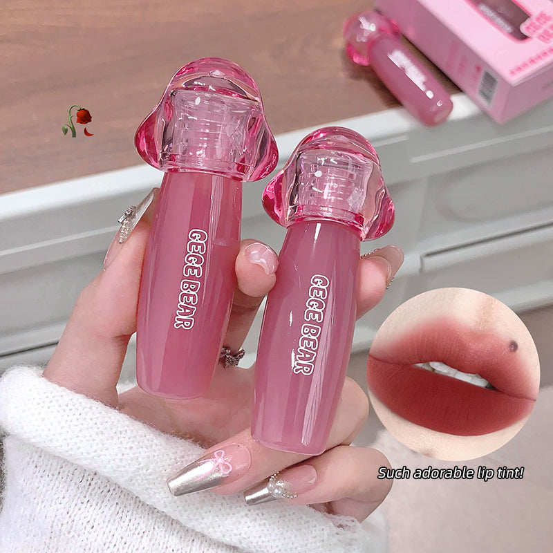 Two pink lip glosses held by a hand with a close-up of lips wearing the product.