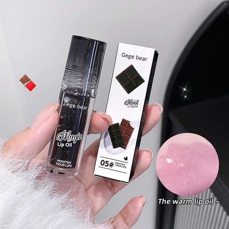 Lip oil with packaging held in a hand, close-up view.