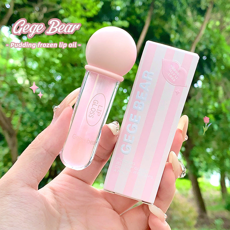 Pink lip oil with 'Gege Bear' branding held by a hand against a blurred green outdoor background.