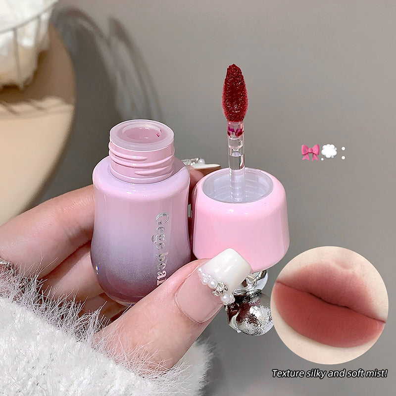 Pink lip balm with applicator held by a hand, close-up shot.