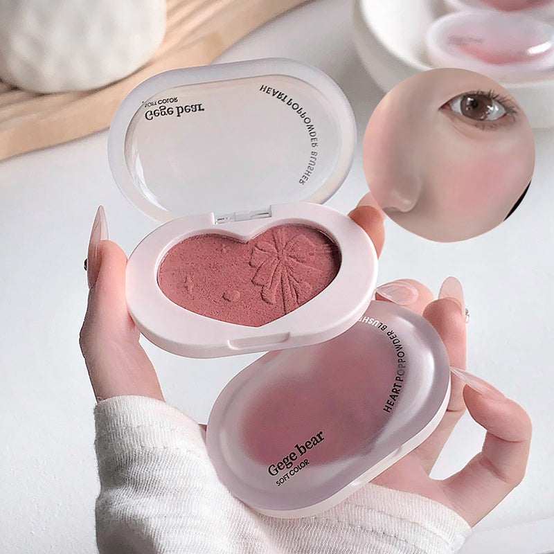 Heart-shaped blush compact held by a hand with a blurred background