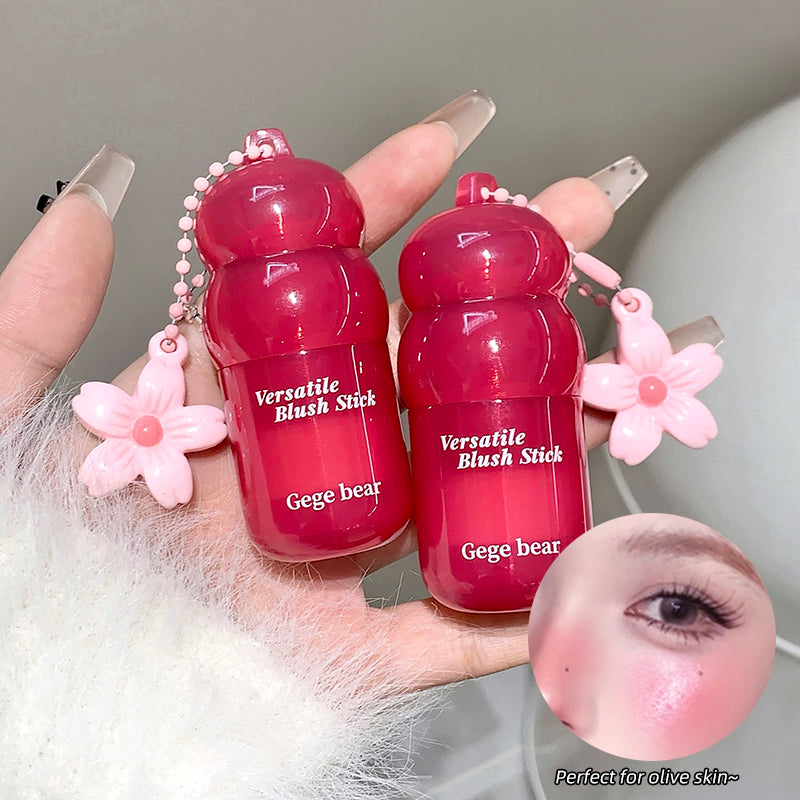 Two red blush sticks with floral designs held by a hand, close-up of skin with blush applied.