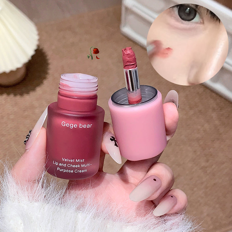 Two cosmetic products, a pink bottle and a pink stick, held by a hand with a blurred background.