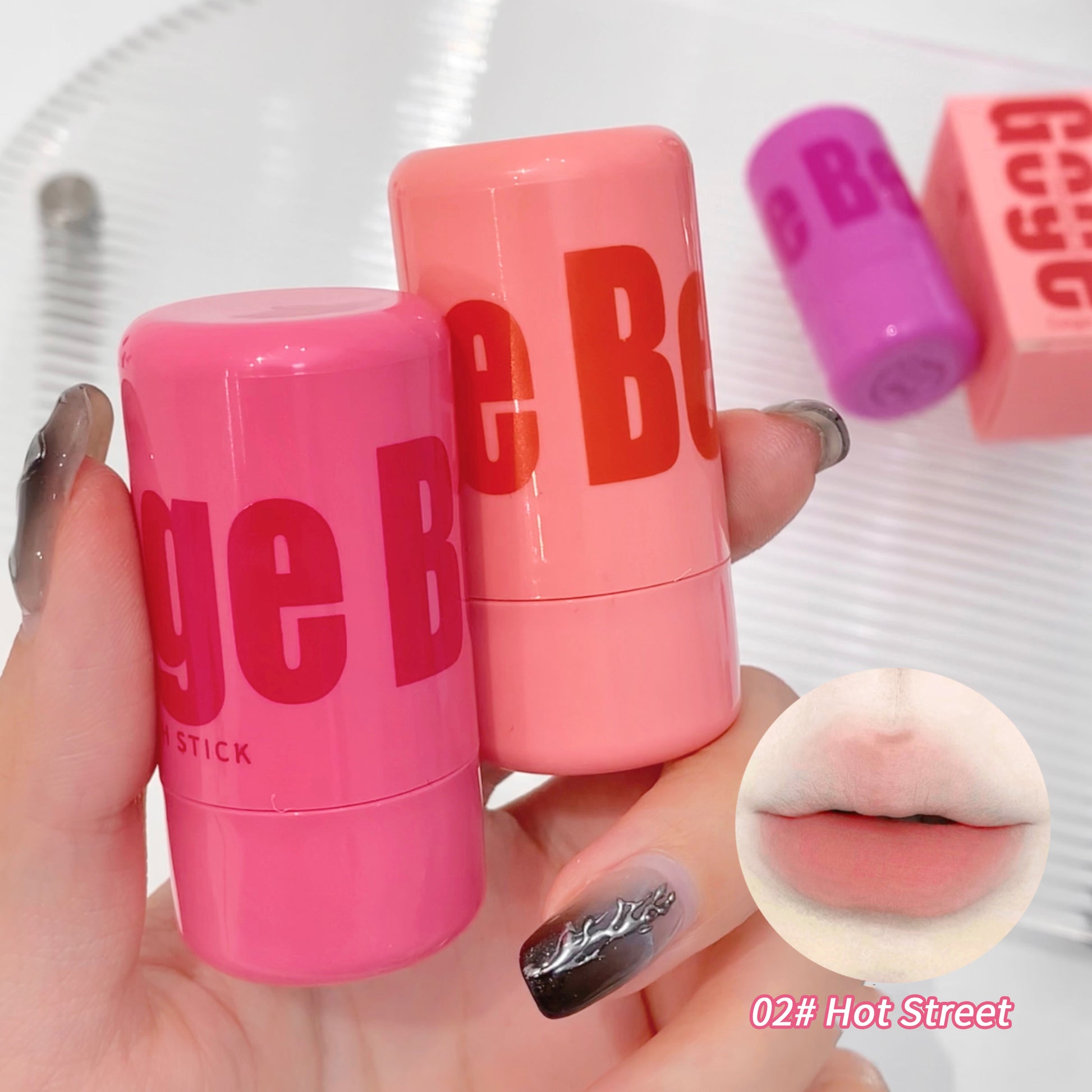 Pink lip balm sticks with 'Be Born' branding held by a hand, showing a close-up of lips with product applied.
