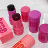 Pink lip balm sticks with visible brand name on a white surface