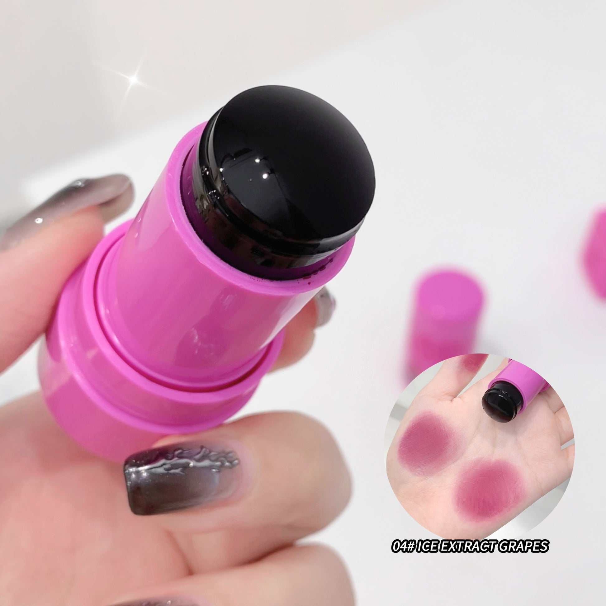 Pink lip balm with black cap held by a hand, close-up on a white background.