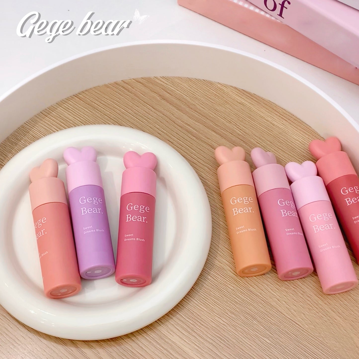 Set of pink and purple lip balms with 'Gege Bear' branding on a wooden surface.