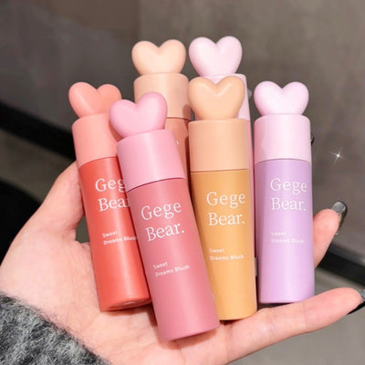 Hand holding six Gege Bear lip products with heart-shaped caps.