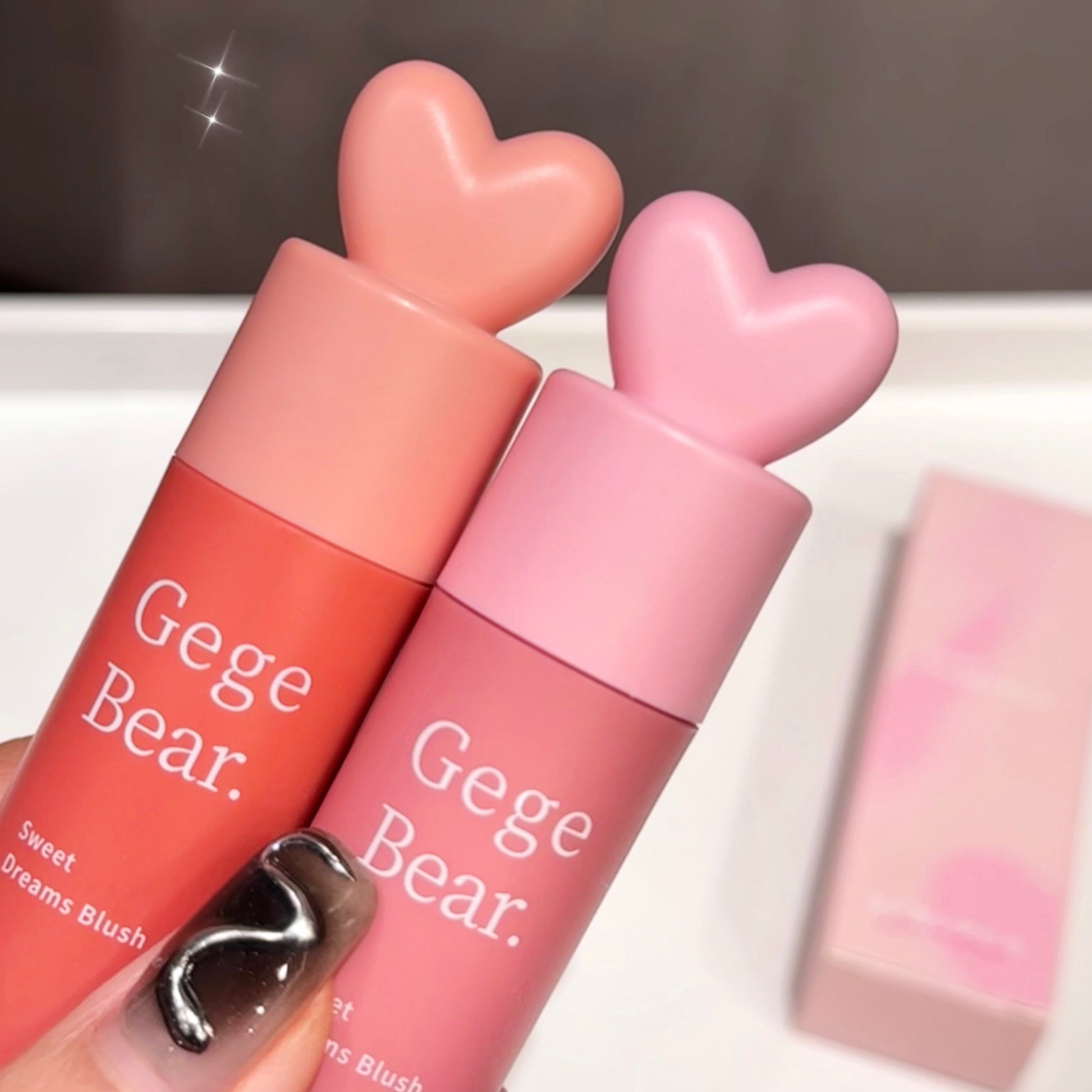 Two Gege Bear lip products with heart-shaped caps on a white surface.