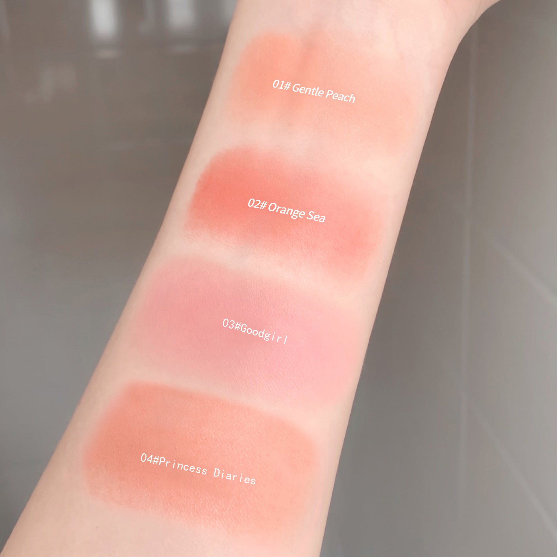 Swatches of different blush colors on a person's arm with labels.