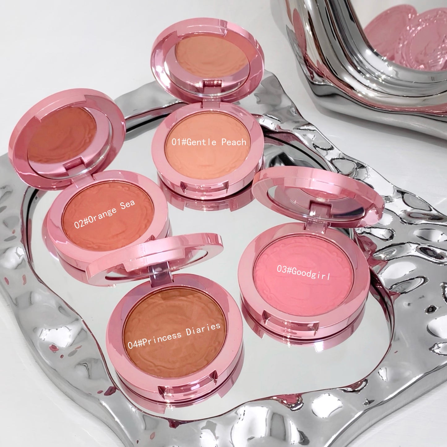 Set of pink makeup blushes with visible color names on a silver tray