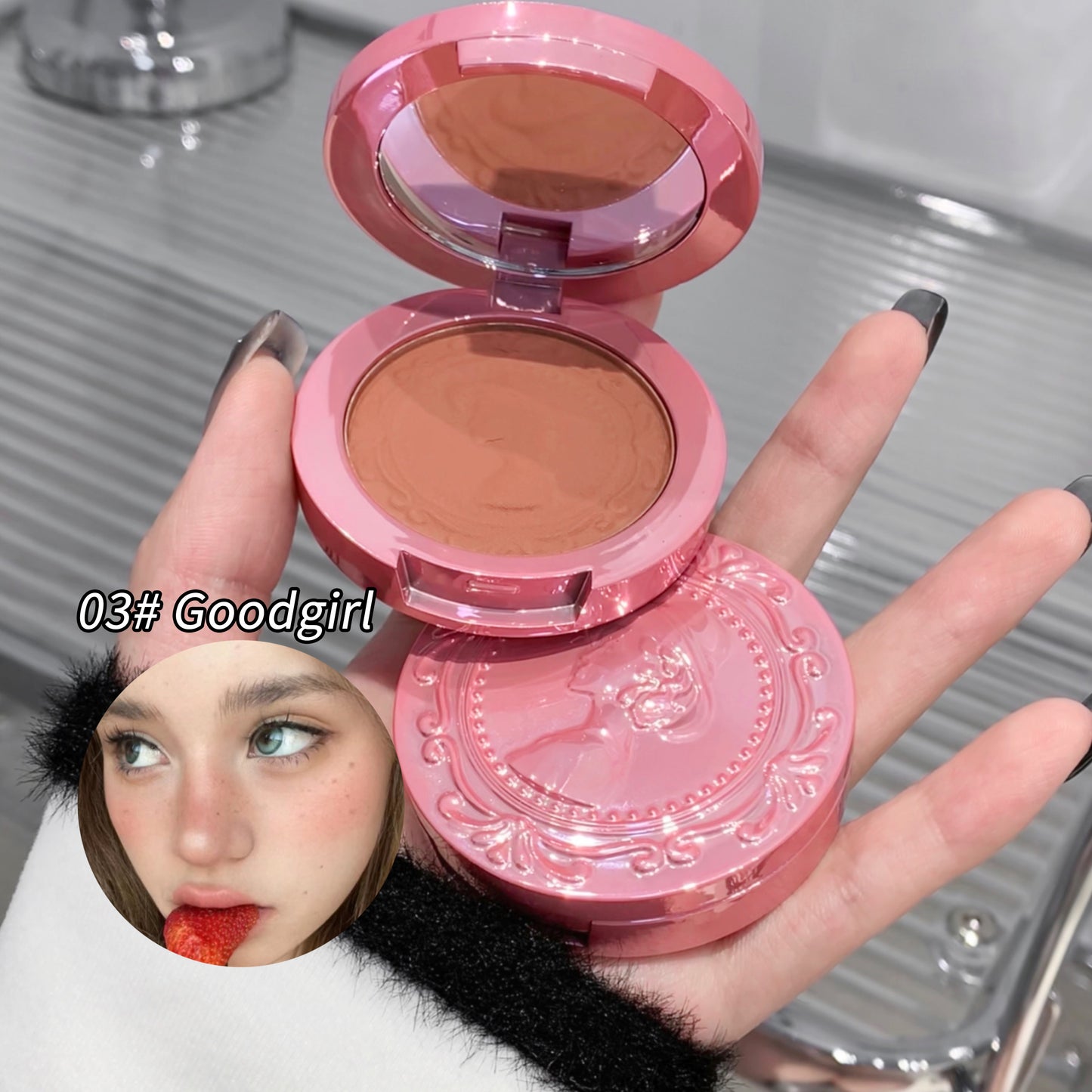 Pink makeup compact with brown powder held by a hand, brand '03# Goodgirl' visible.