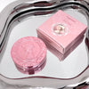 Pink compact mirror and its packaging on a reflective surface