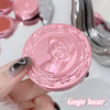 Pink compact mirror with decorative design held by a hand, with 'Gee bear' branding.