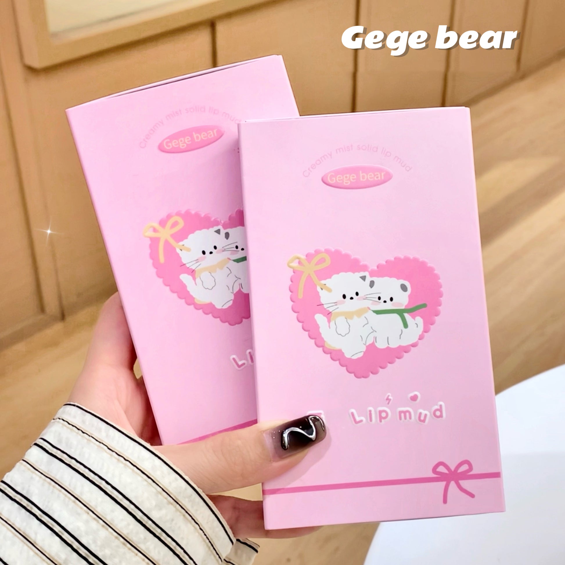 Two pink lip balm packages with a cartoon bear design held by a hand.