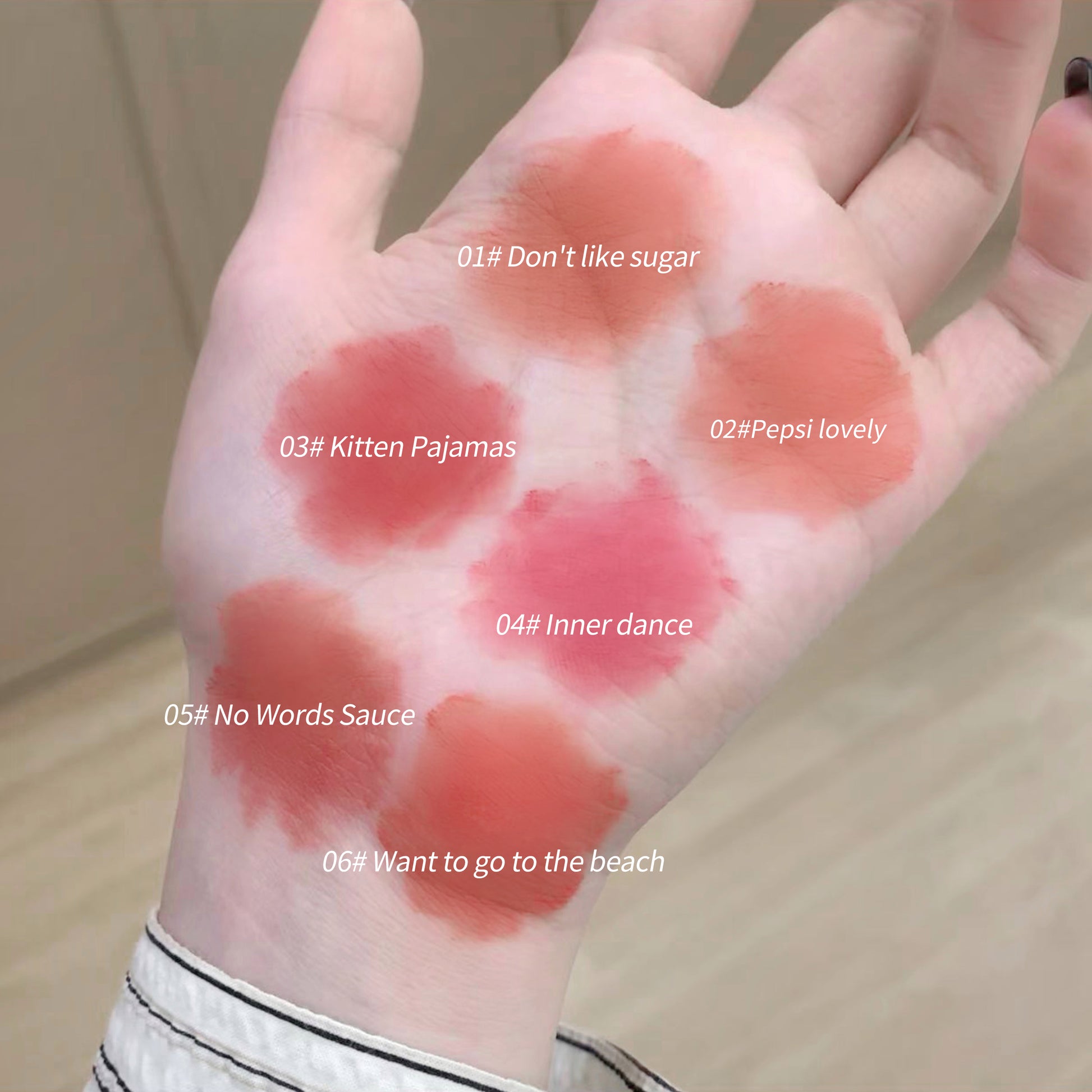 Hand with various colored blushes applied in circular patterns, labeled with names.
