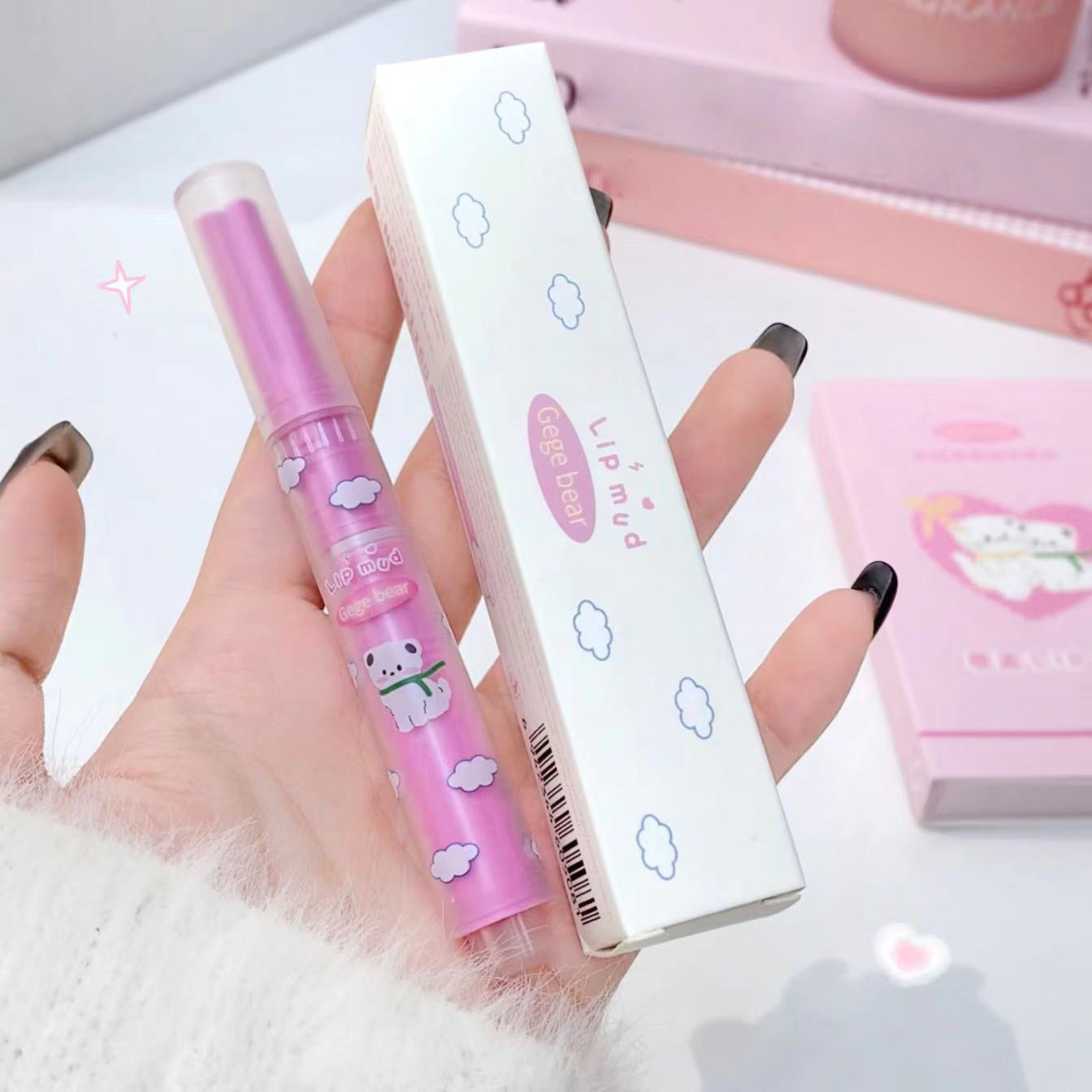 Pink lip balm with a cute design held by a hand against a light background