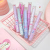 Set of pastel-colored pens with cartoon designs in a pink holder on a light background