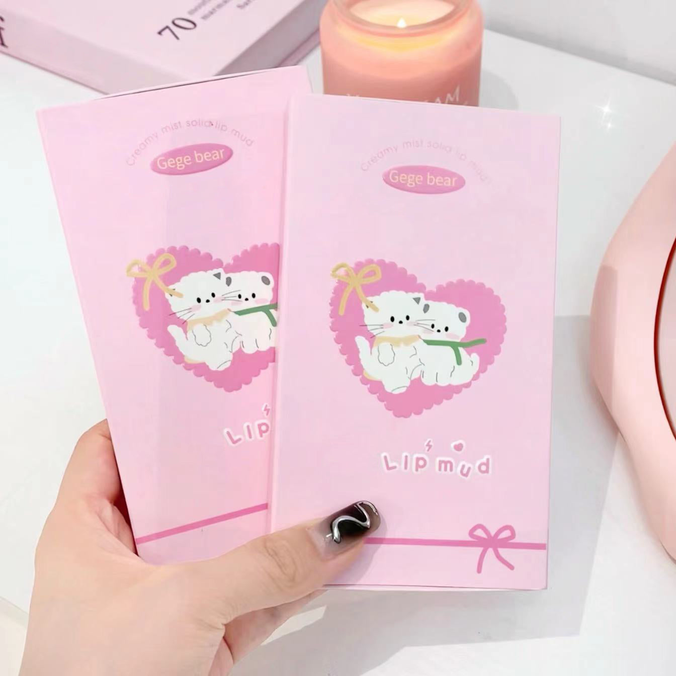 Two pink lip balm packages with a cartoon bear design held by a hand.