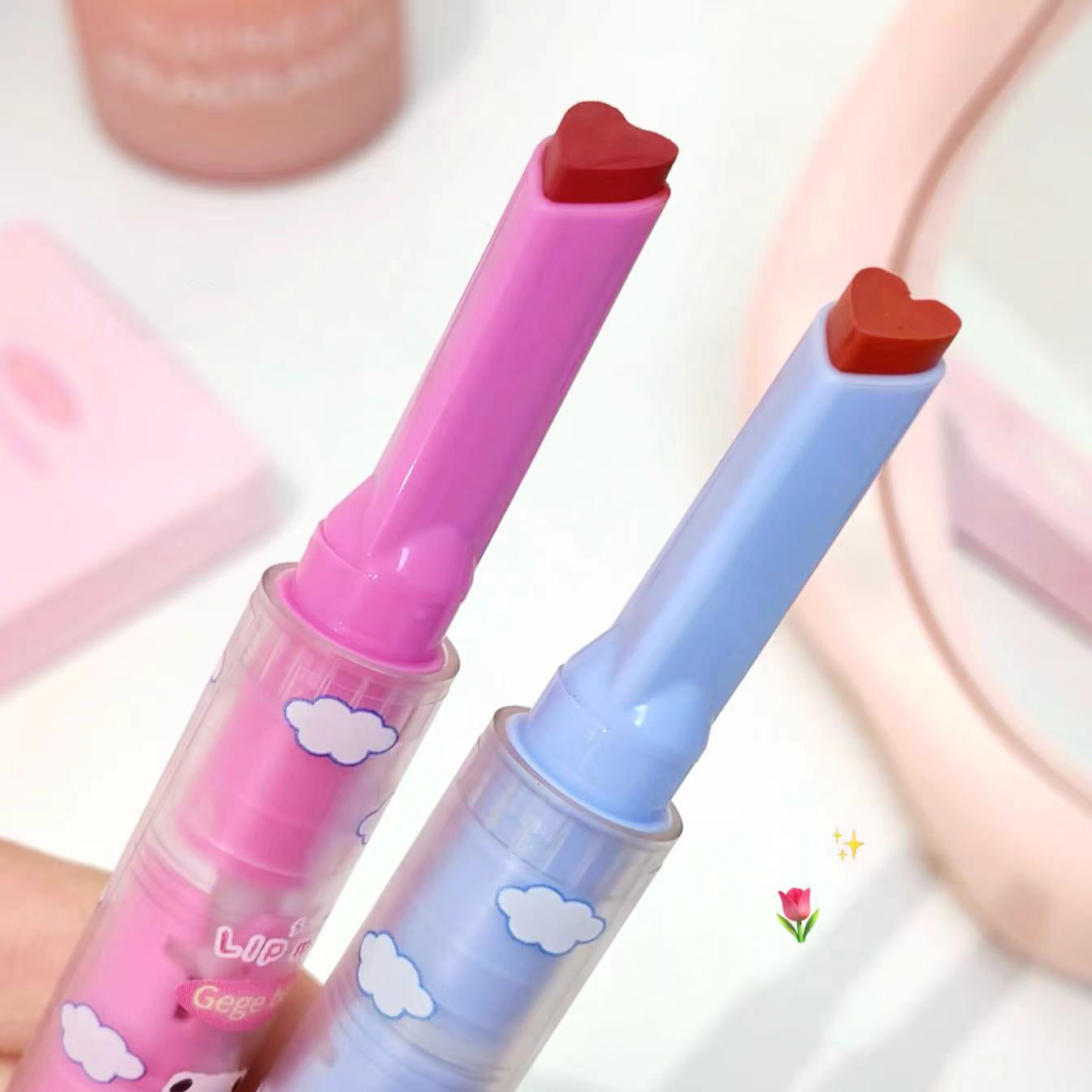 Two colorful lip glosses with heart-shaped caps on a light background