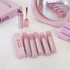 Pink lip gloss set with packaging on a white surface