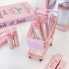 Pink cosmetic products in a mini shopping cart with 'Book of Jam' packaging on a white background