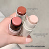 Three makeup sticks held in a hand with labels indicating their types and textures.