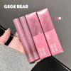 Pink GEGE BEAR makeup products held by a hand against a dark background