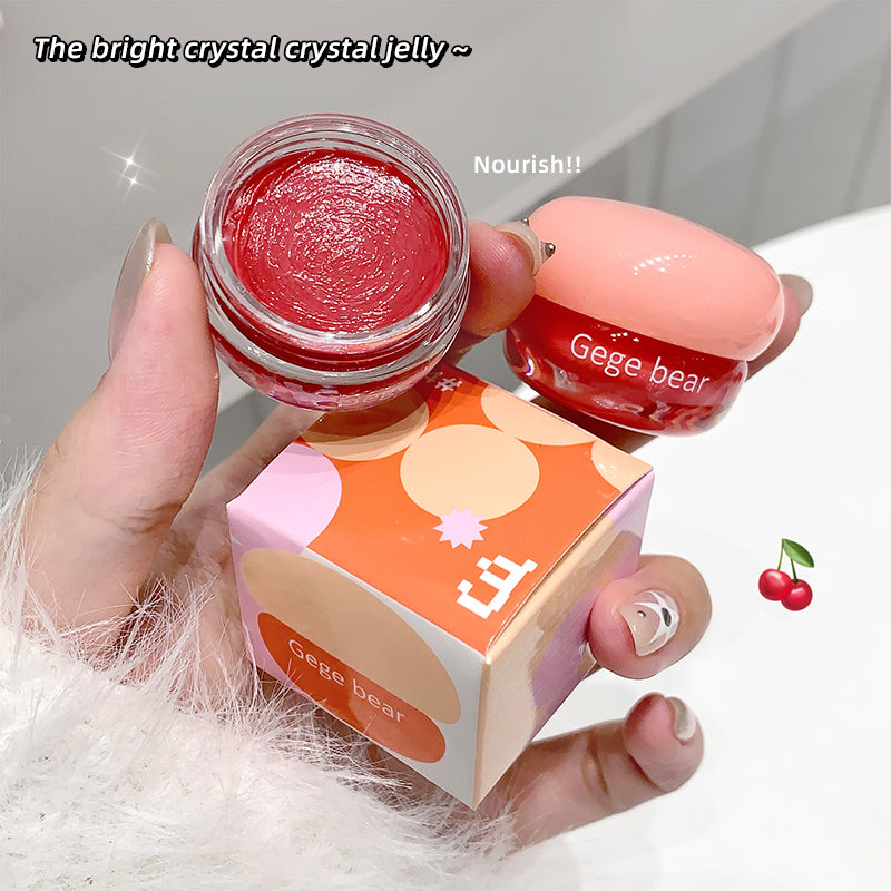 Hand holding a small jar of red jelly product with 'Gege bear' branding, next to its packaging.