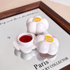 White floral-shaped containers with red liquid on a white tray with 'Paris' text