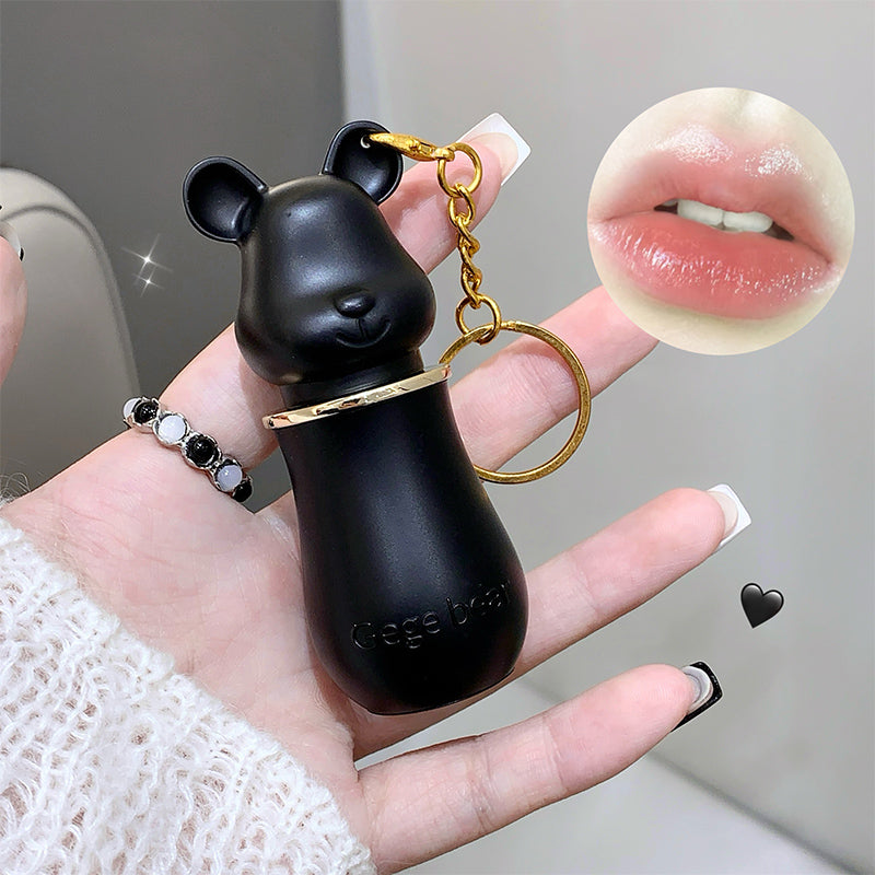 Black bear-shaped keychain held in a hand with a close-up of lips inset.
