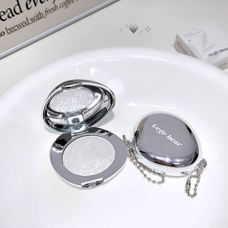 Compact mirror with glittery powder and 'Geege bear' branding on a white surface.