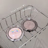 Compact powder with 'Geege bear' branding on a metal rack.