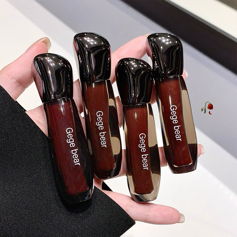 Four lip glosses with 'Gege bear' branding held in a hand against a neutral background.