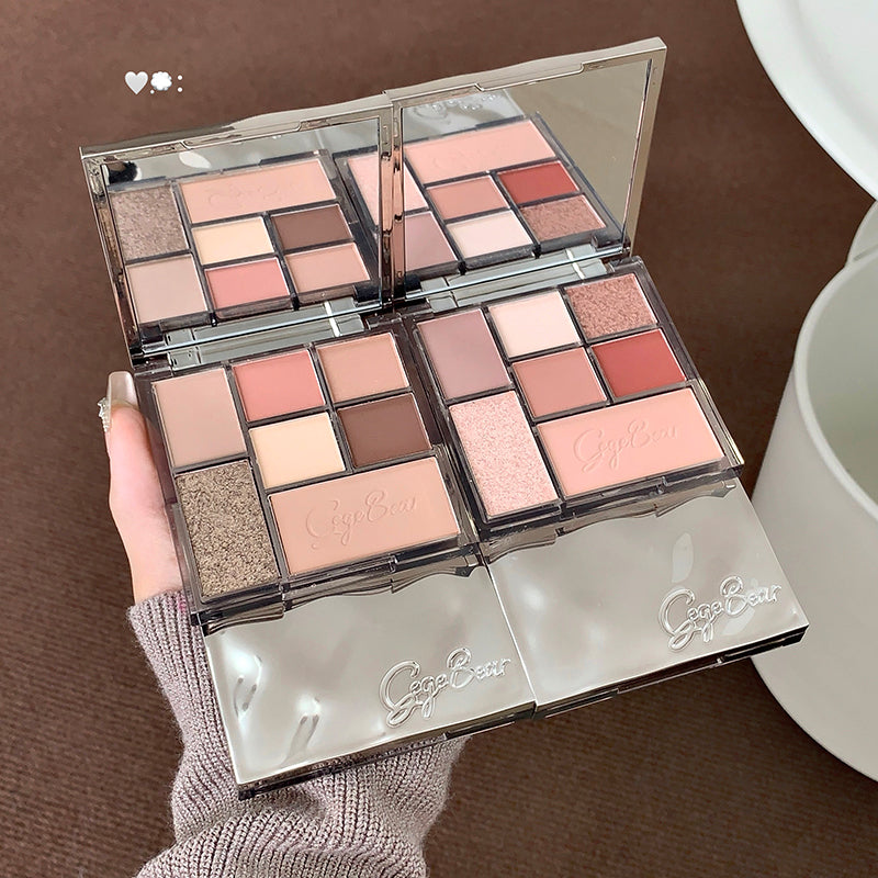 Makeup palette with various shades held by a hand on a brown surface