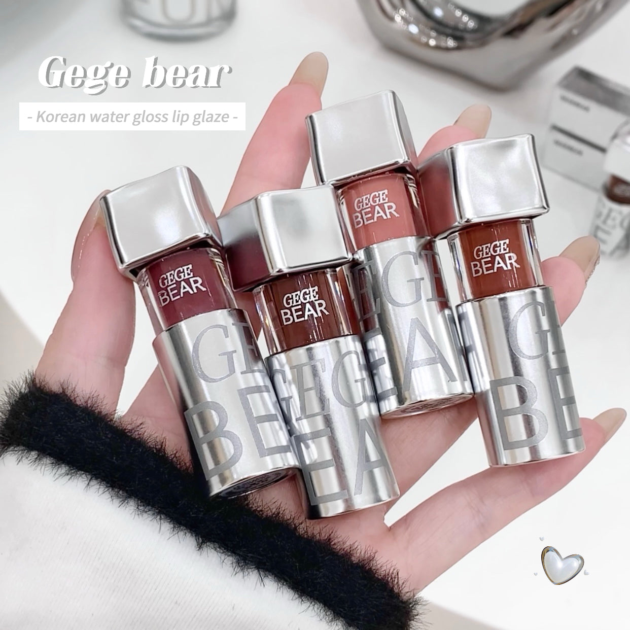 Hand holding four 'Gege Bear' lip glosses with a blurred background