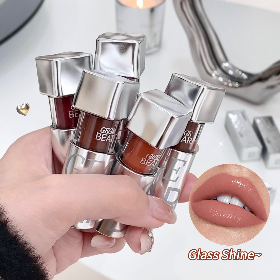 Hand holding four lip glosses with a close-up of a lip wearing one of them, set against a blurred background.