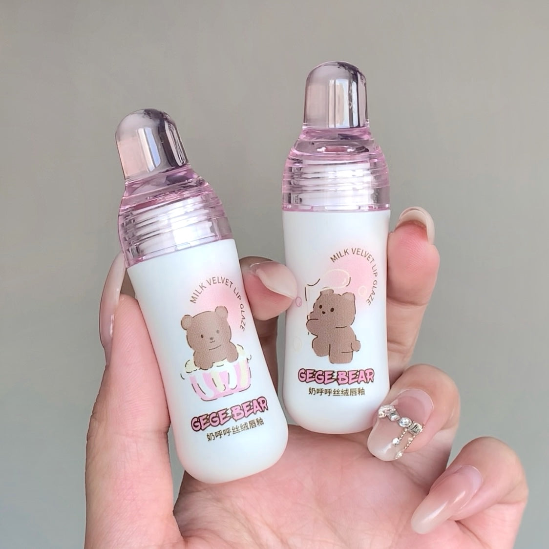 Two small bottles with bear design labels held in a hand against a neutral background