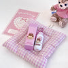 Two bottles with bear designs on a checkered purple and white blanket, next to a pink card and small plush toy.