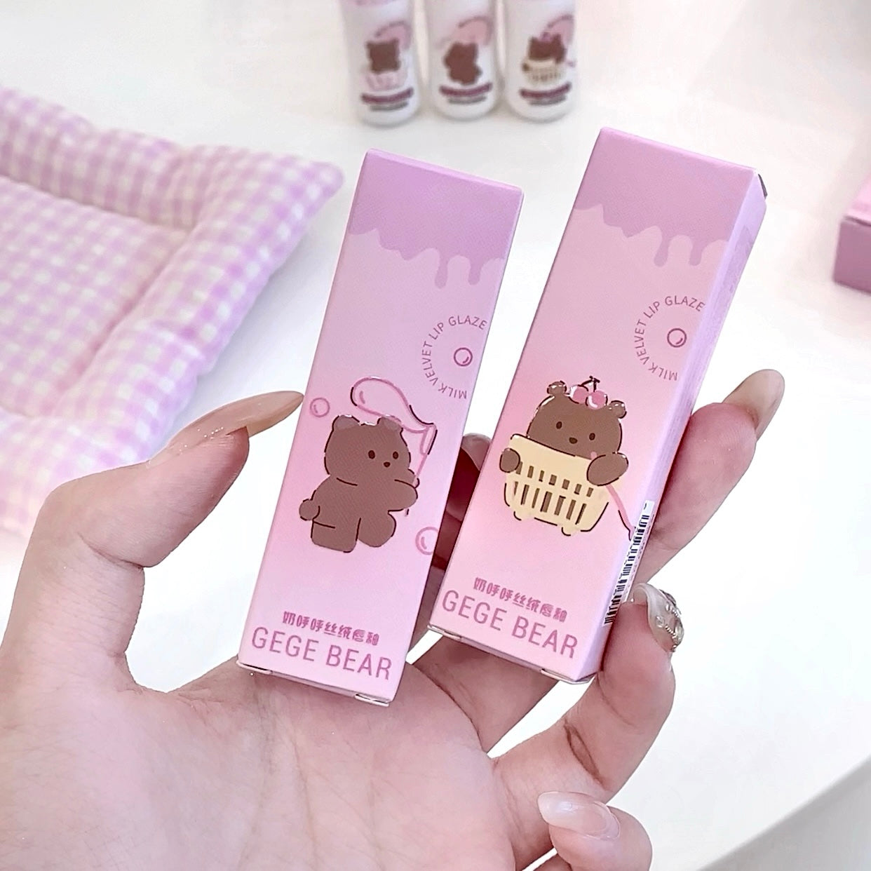 Two pink boxes with bear illustrations held by a hand on a light background