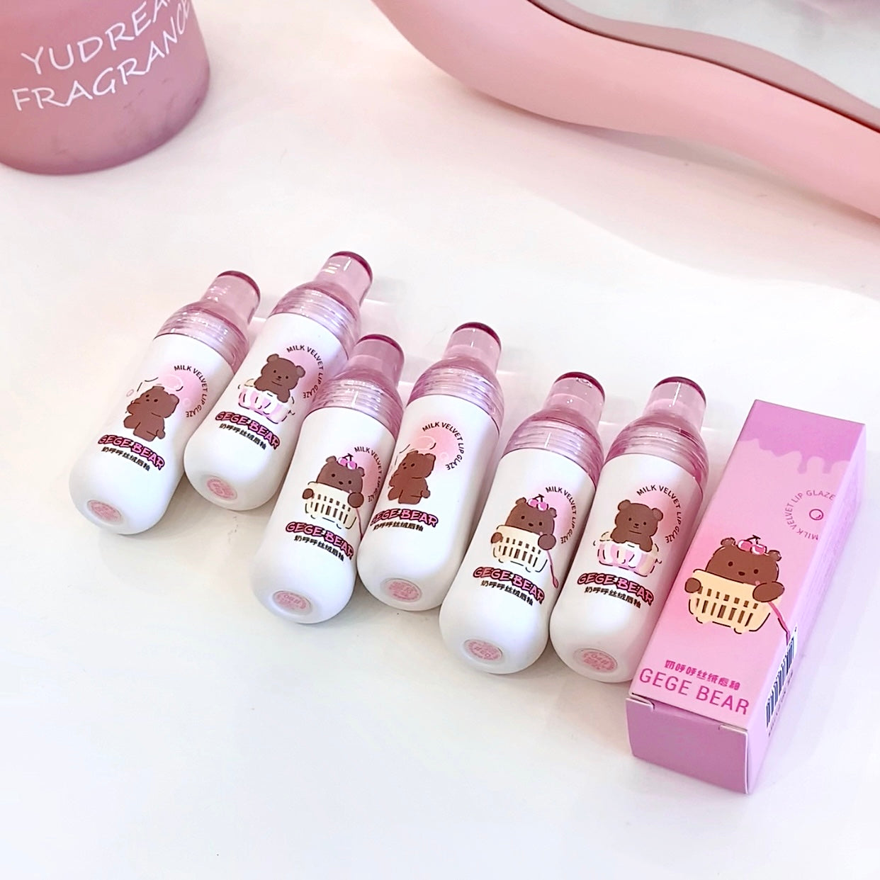 Set of white bottles with bear designs and a pink box on a light background
