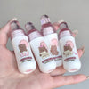 Four small bottles with bear illustrations and text held in a hand against a neutral background