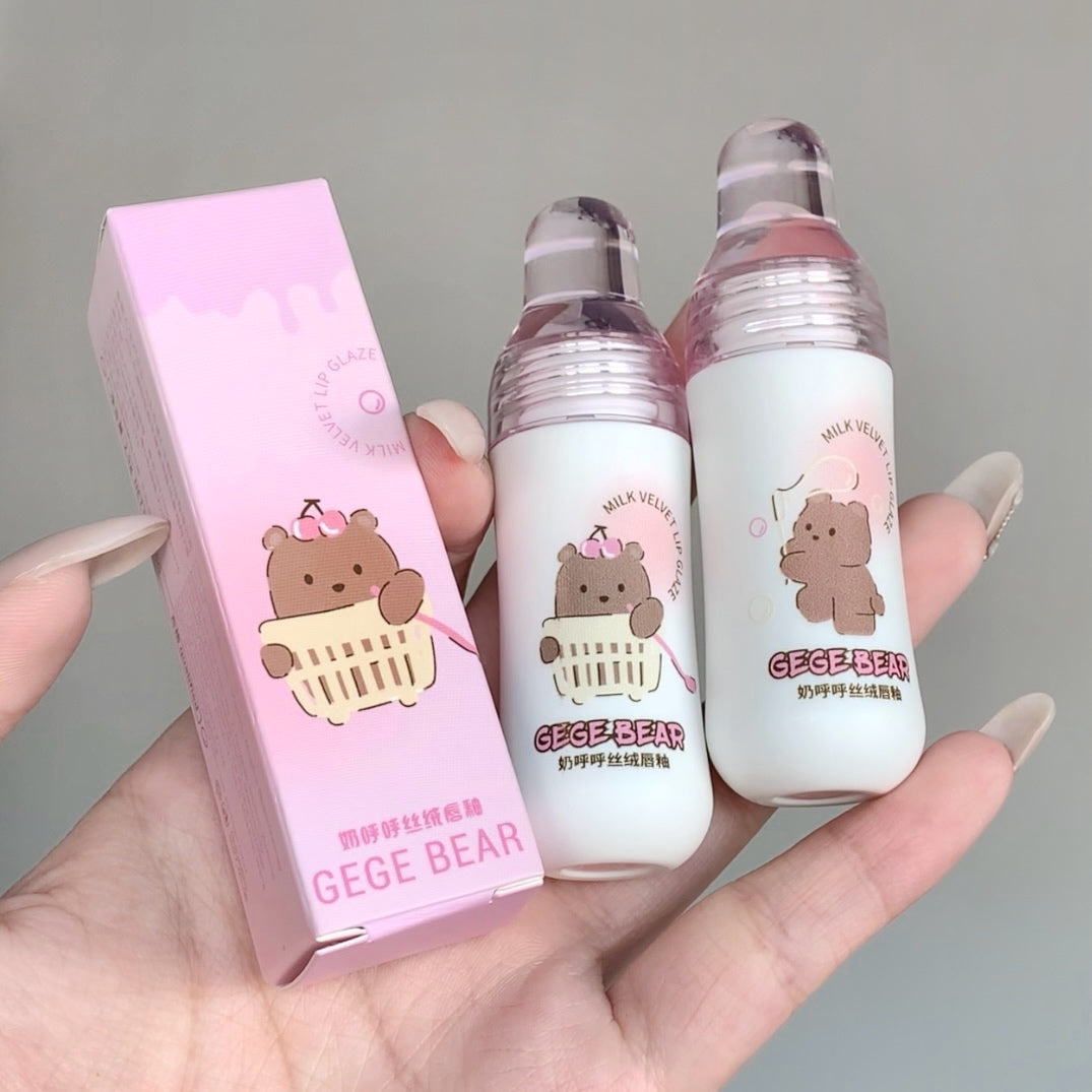 Two small bottles with a pink box featuring a bear design held in a hand against a gray background.
