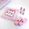 Set of lip balms and boxes on a pink checkered cushion with a white background