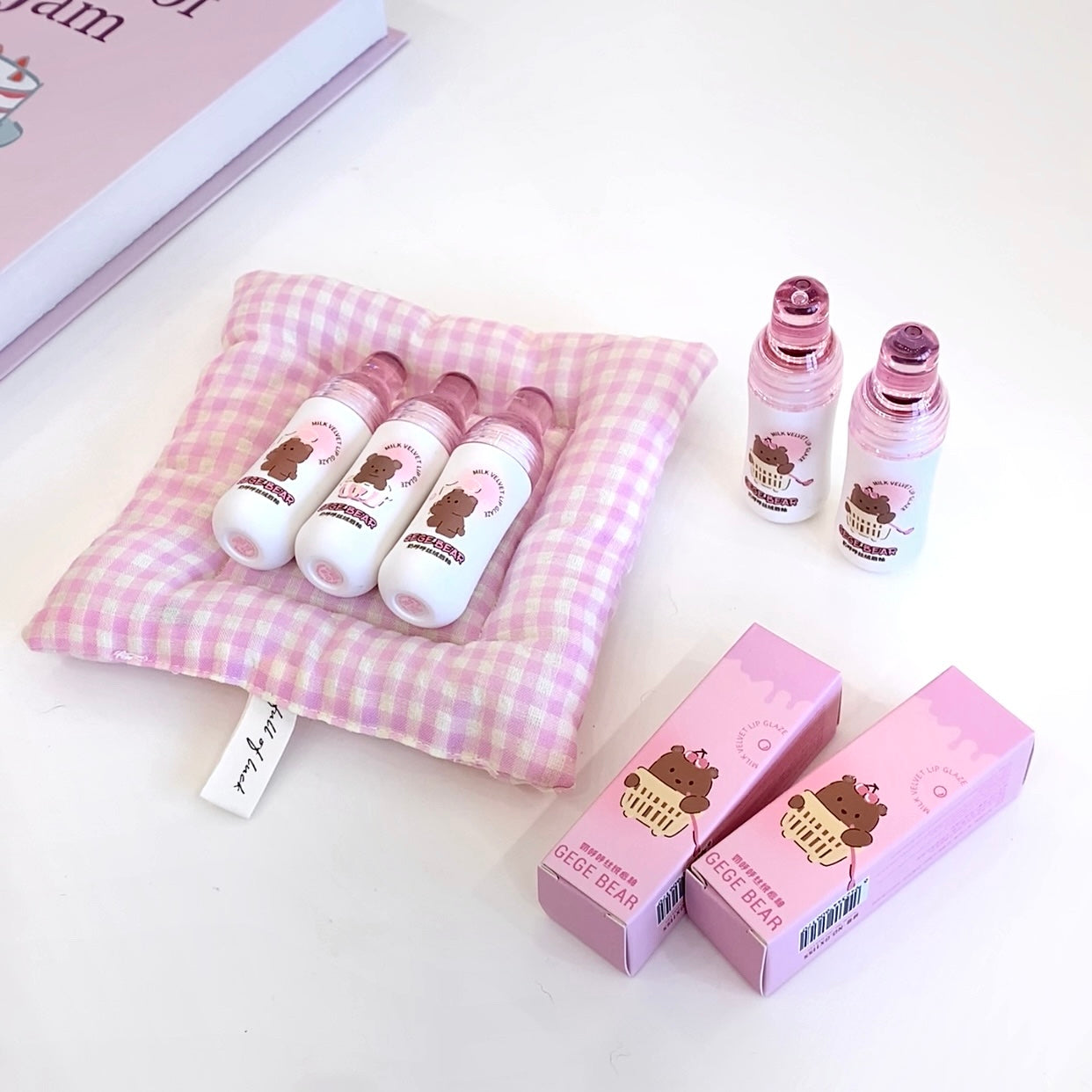 Set of lip balms and boxes on a pink checkered cushion with a white background